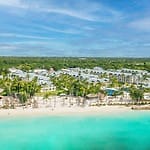 Aerial view of a beachfront resort, ideal for a destination wedding, with white buildings and turquoise water.