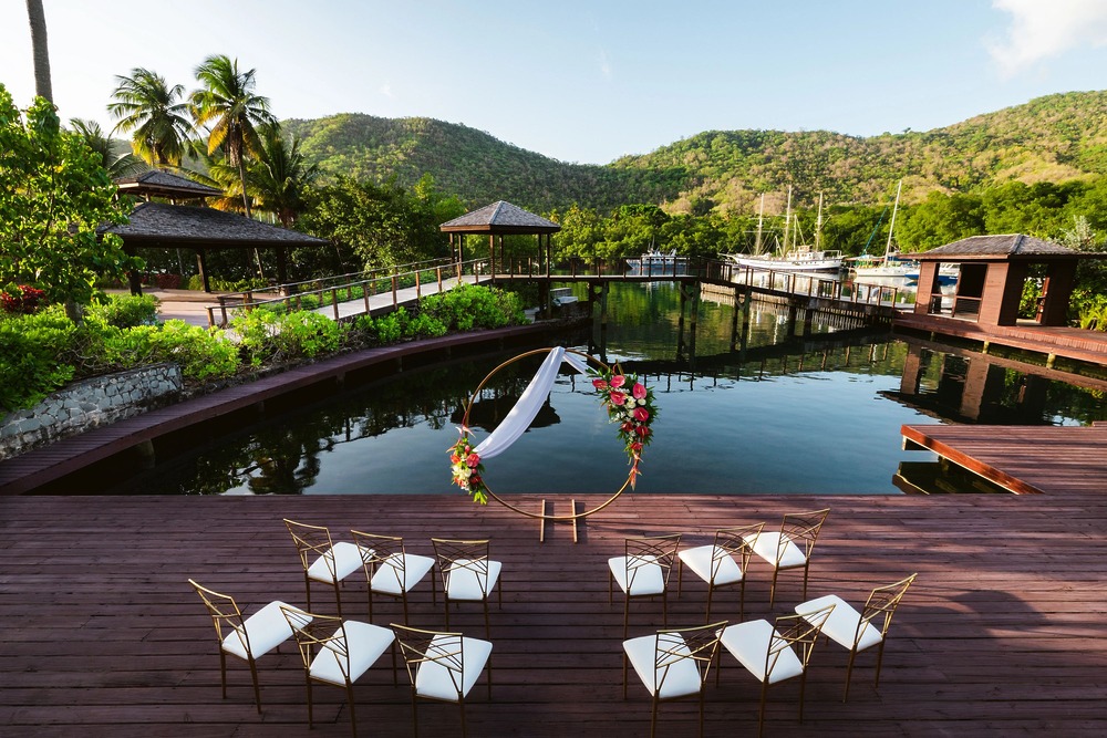 Chairs arranged by a decorative arch on a deck, evoking a luxury destination wedding atmosphere.