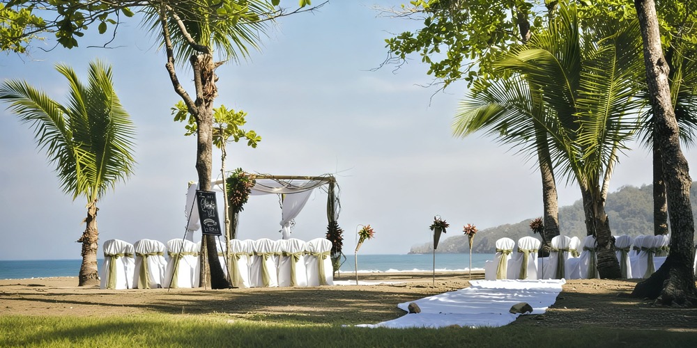 Elegant beachfront destination wedding setup featuring white chairs and a beautiful archway, set at one of Costa Rica’s stunning wedding venues.