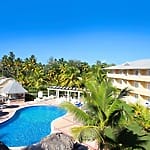 Budget-friendly all-inclusive resort with pool, palm trees, yellow building&mdash;ideal for destination weddings.