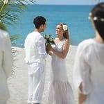 Bride and groom hold hands on a sandy beach during a beautiful destination wedding in Panama City.