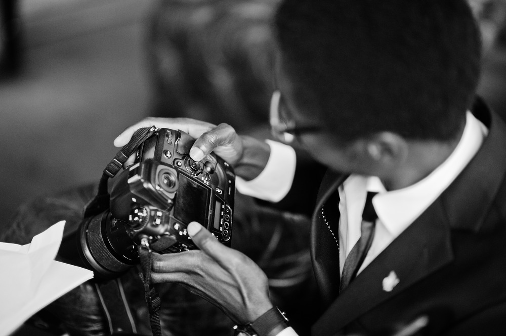 A person in a suit, captured from above, adjusts camera settings while preparing to film a wedding or destination wedding.