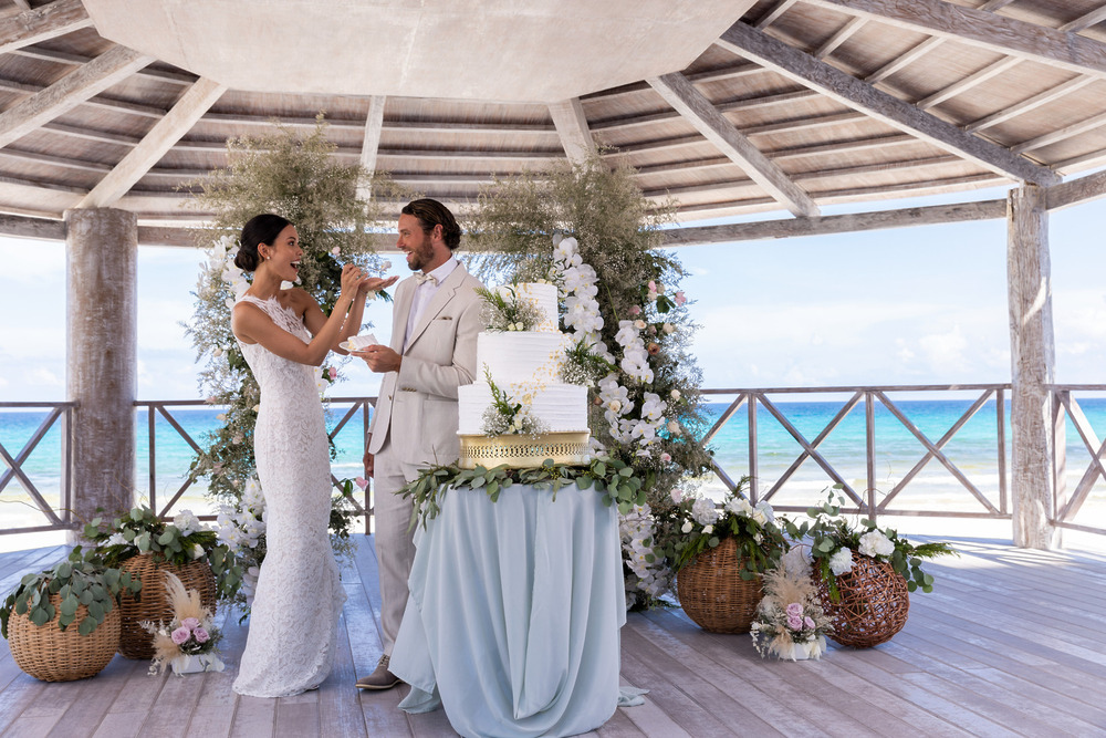 The bride and groom enjoy sharing cake together under a gazebo during their destination wedding in Cancun, included in their wedding package.