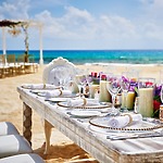 An elegant table arrangement for a destination wedding in Cancun, beautifully adorned with glassware, candles, and fresh flowers.