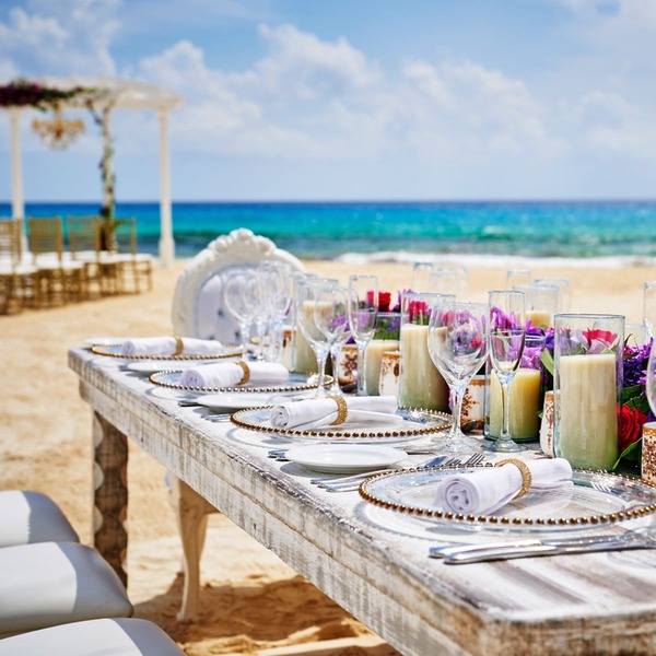 An elegant table arrangement for a destination wedding in Cancun, beautifully adorned with glassware, candles, and fresh flowers.