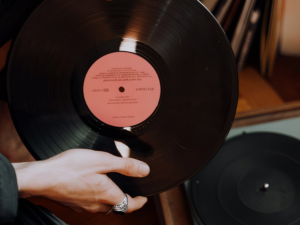 At a destination wedding, someone carefully holds a vinyl record above the turntable, getting ready to play it.