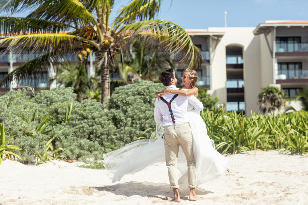 A groom lifts his bride on a sandy beach, creating the perfect scene for a dreamy destination wedding in Tulum, Mexico.