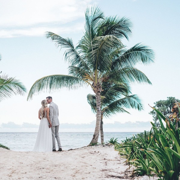 A couple in wedding attire stands on a sandy path at one of Tulum’s top destination wedding locations.