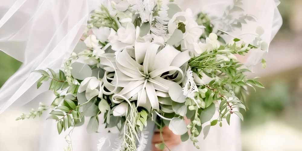 A bride holding a stunning wedding bouquet of white blooms and lush greenery, wrapped in elegant charm—perfect for a spring destination wedding.