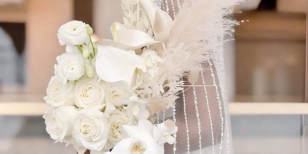 A stunning spring bouquet for a wedding or destination wedding, featuring elegant white roses, graceful calla lilies, and delicate decorative beads.