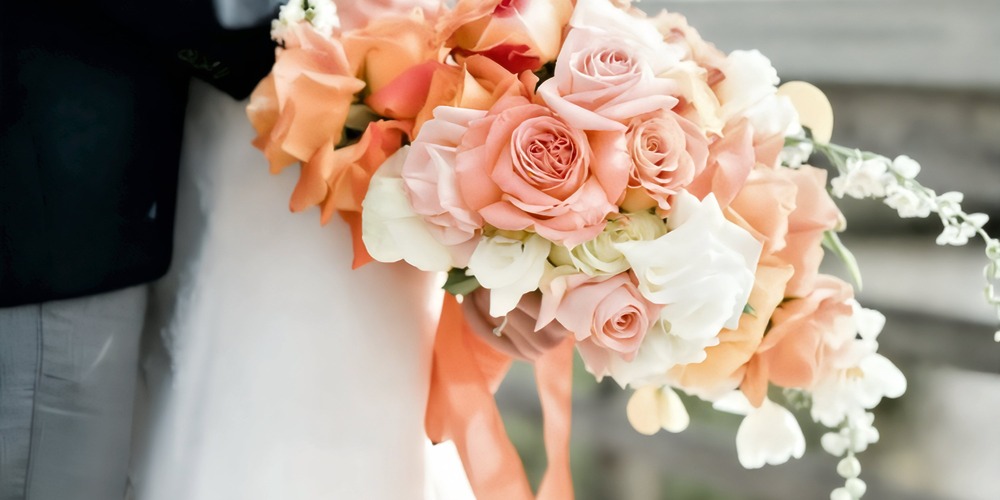 A close-up view of a vibrant spring bouquet, held by someone dressed in formal attire at a destination wedding.