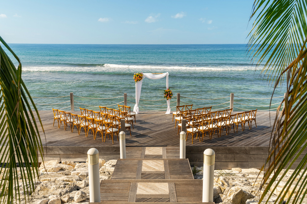 Rows of chairs and a beautifully adorned arch are set up by the ocean in Montego Bay, ready for a stunning destination wedding.