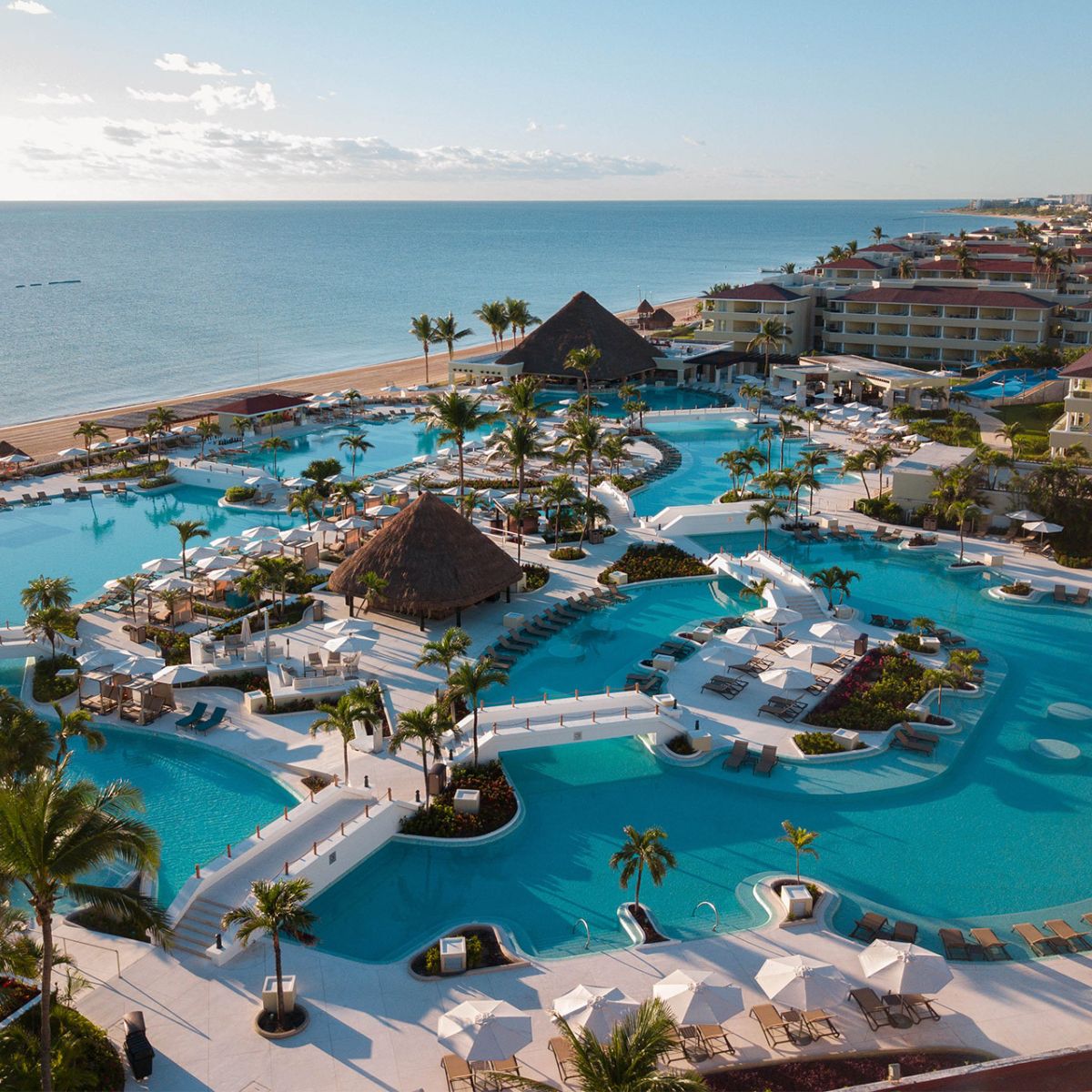 Aerial view of a beachfront resort, perfect for a destination wedding, with pools, palm trees, and lounges.