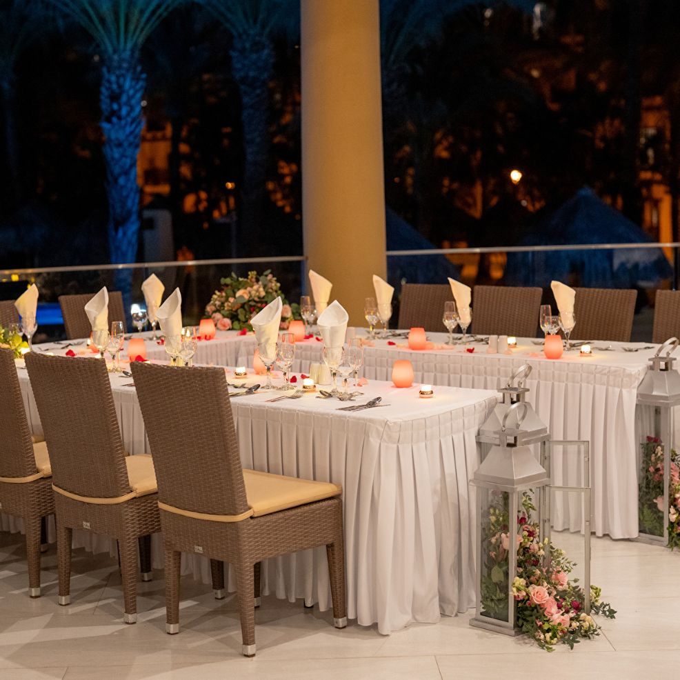Chic destination wedding dining scene with white tablecloths, candles, and elegant lantern centerpieces.
