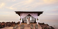 A wedding couple poses under a seaside gazebo at sunset for their destination wedding at Royalton Blue Waters.