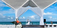 Destination wedding altar at Royalton Blue Waters with white drapes, flowers, and a beachside ocean view.