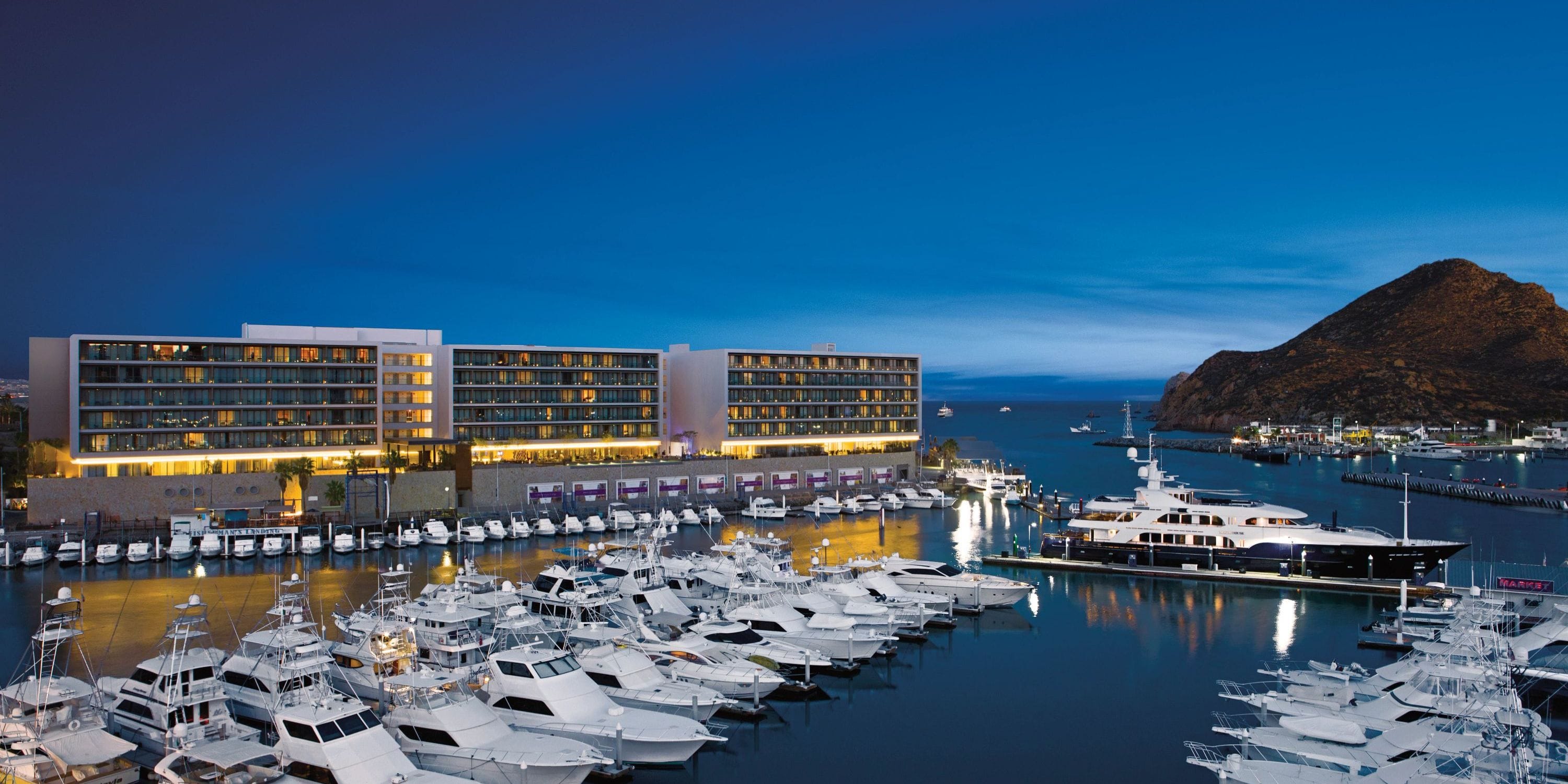 Breathless Cabo San Lucas: modern hotel by marina at dusk, perfect for a destination wedding.