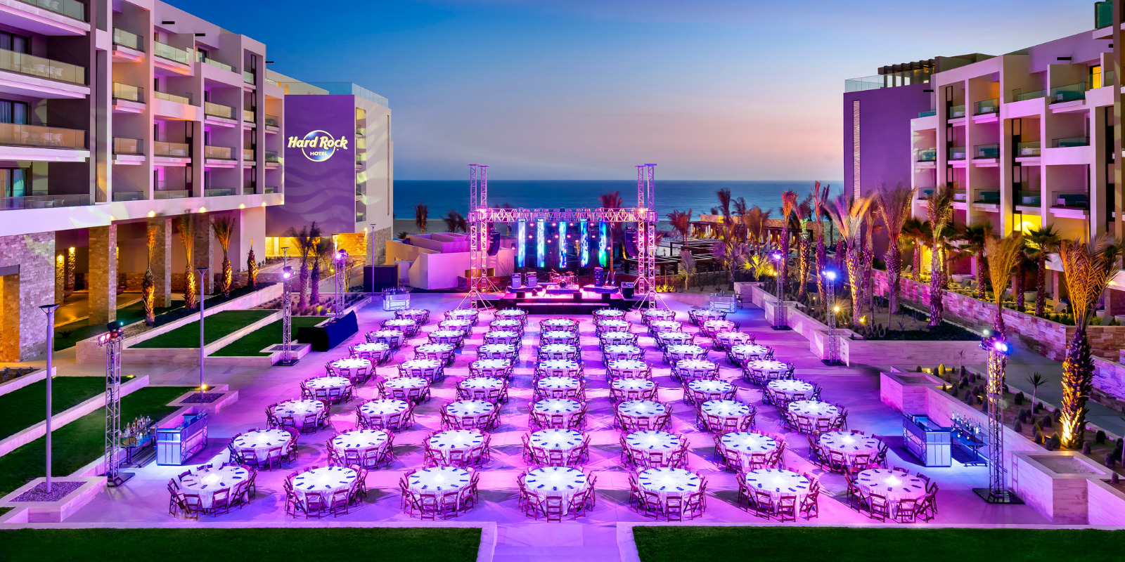 A large outdoor area, set for a destination wedding at Hard Rock Los Cabos, with tables and chairs at dusk.