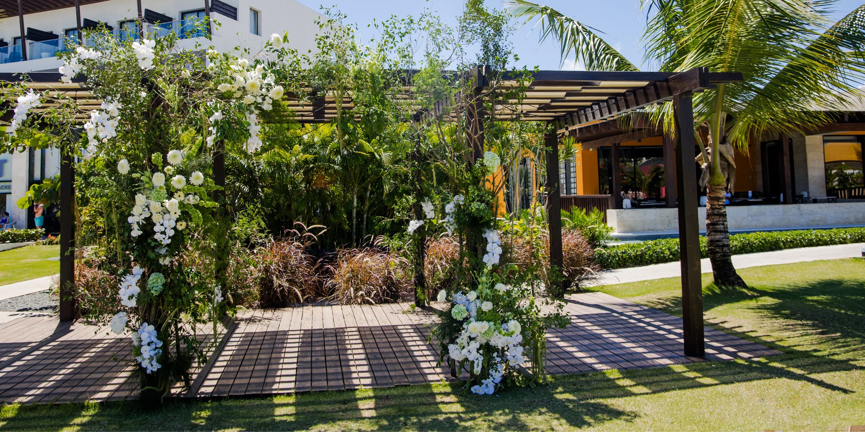 Dreams Macao Beach wedding pergola decorated with white flowers and greenery in a lush garden setting.