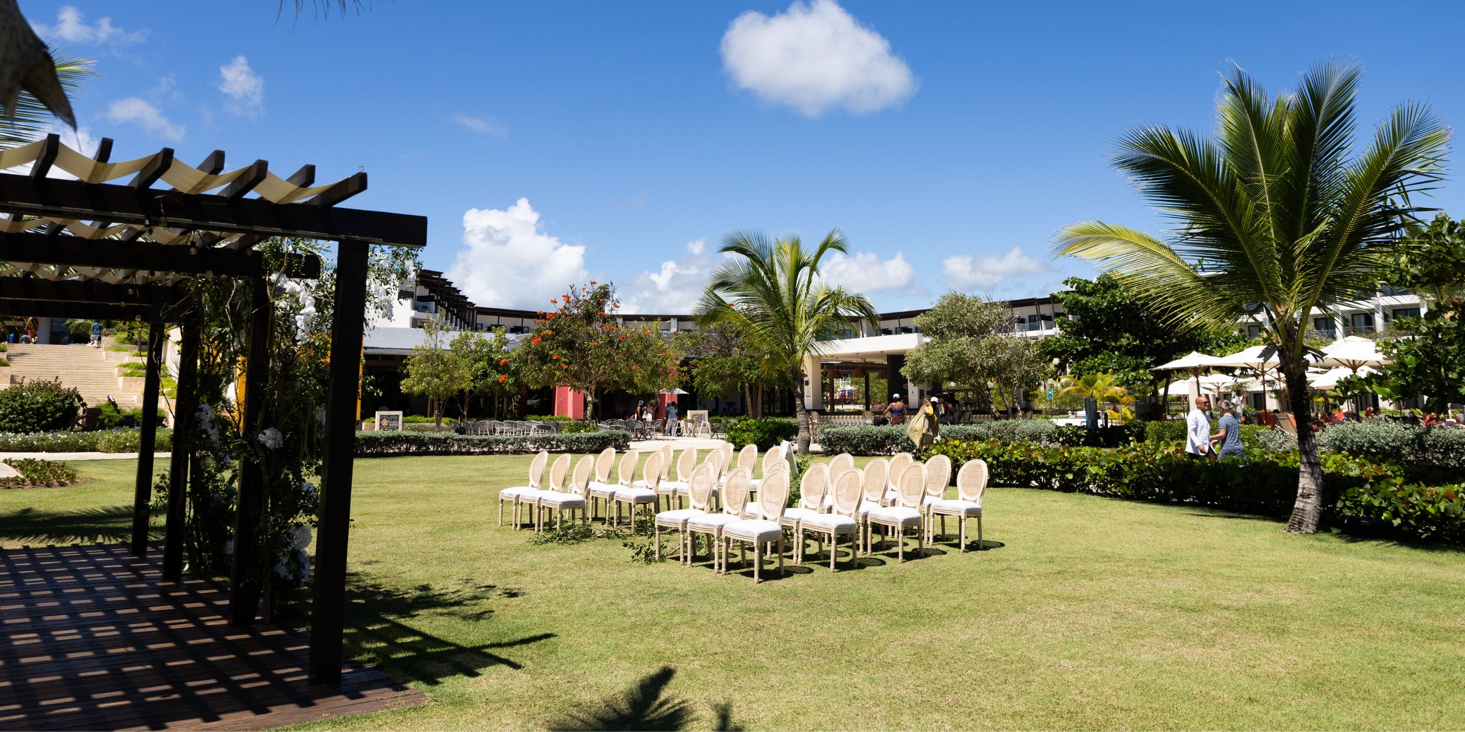 Chairs set up on the lawn at Dreams Macao Beach for a destination wedding under palm trees and sky.