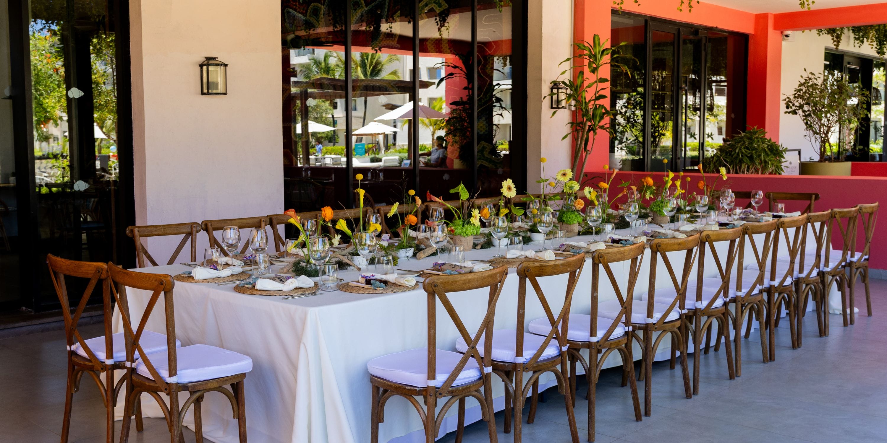 A dining table with wooden chairs and floral decor set for a destination wedding at Dreams Macao Beach.