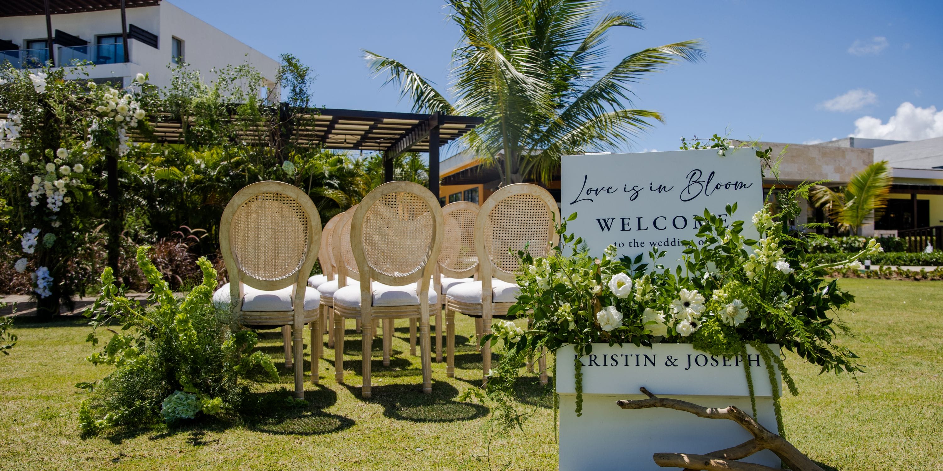 Destination wedding ceremony at Dreams Macao Beach with wooden chairs, floral accents, and a welcome sign.