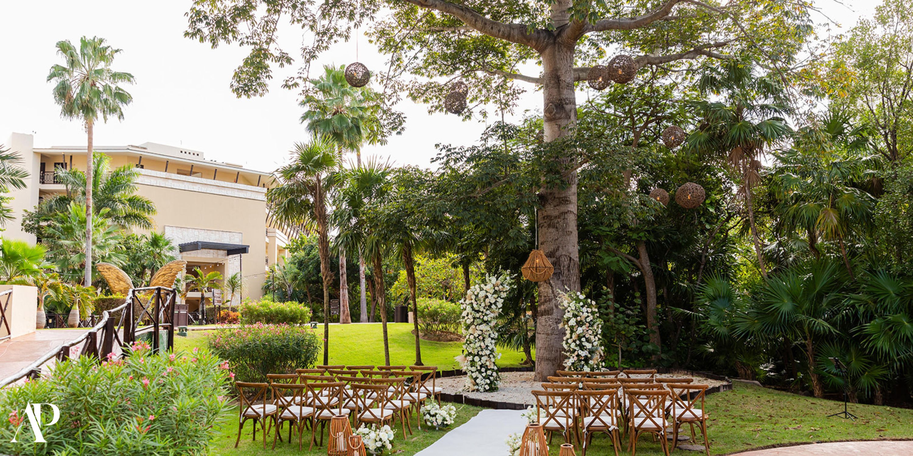 Destination wedding at Dreams Riviera Cancun with wooden chairs, floral arch, and striking tree centerpiece.