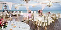 Dreams Riviera Cancun destination wedding with elegant tables, gold chairs, and sparkling chandeliers.