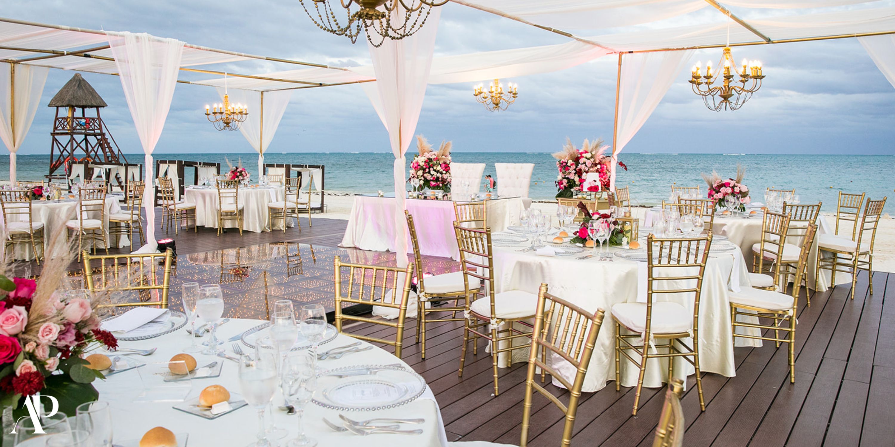 Dreams Riviera Cancun destination wedding with elegant tables, gold chairs, and sparkling chandeliers.