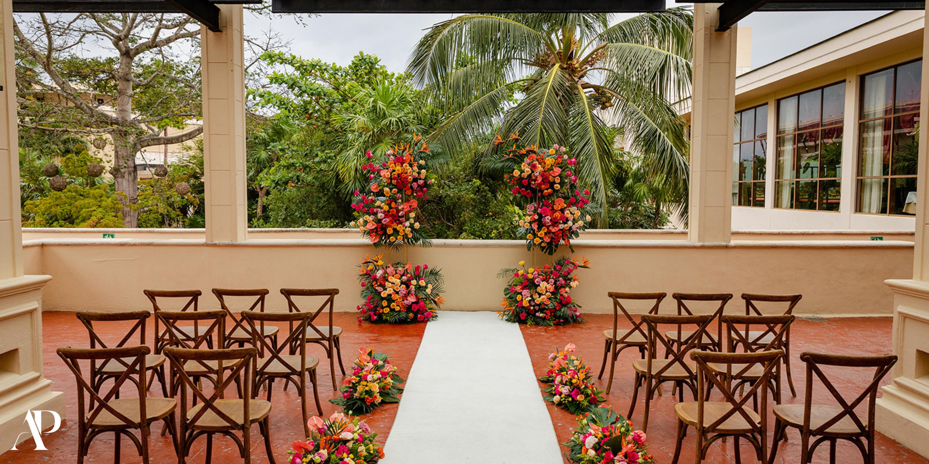 Destination wedding at Dreams Riviera Cancun featuring wooden chairs, lush florals, and a white aisle runner.
