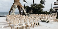 Chairs set up for a destination wedding by the ocean at Dreams Riviera Cancun, adorned with flowers.