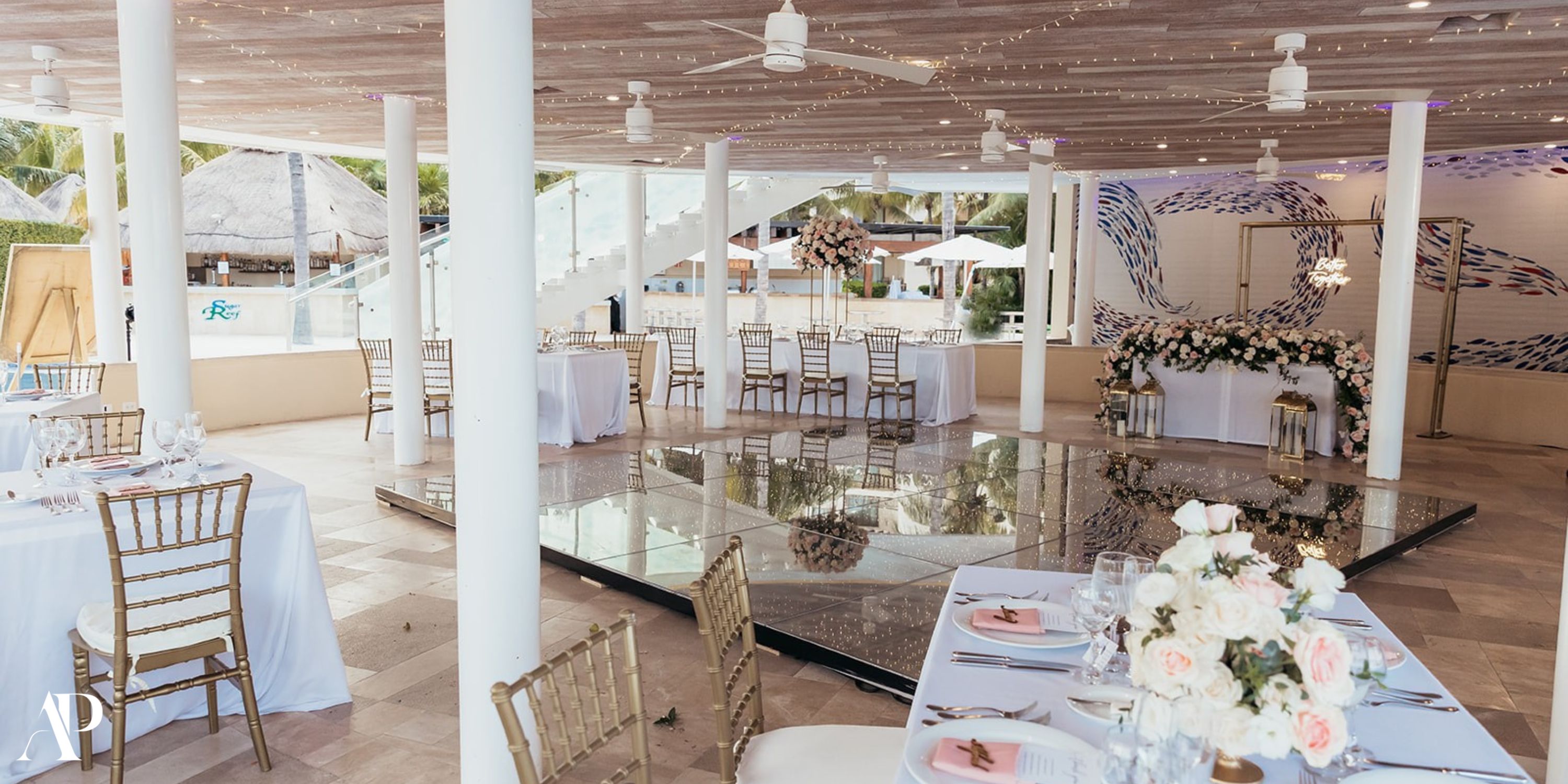 Dreams Riviera Cancun destination wedding: elegant reception with white tables, gold chairs, glass dance floor.