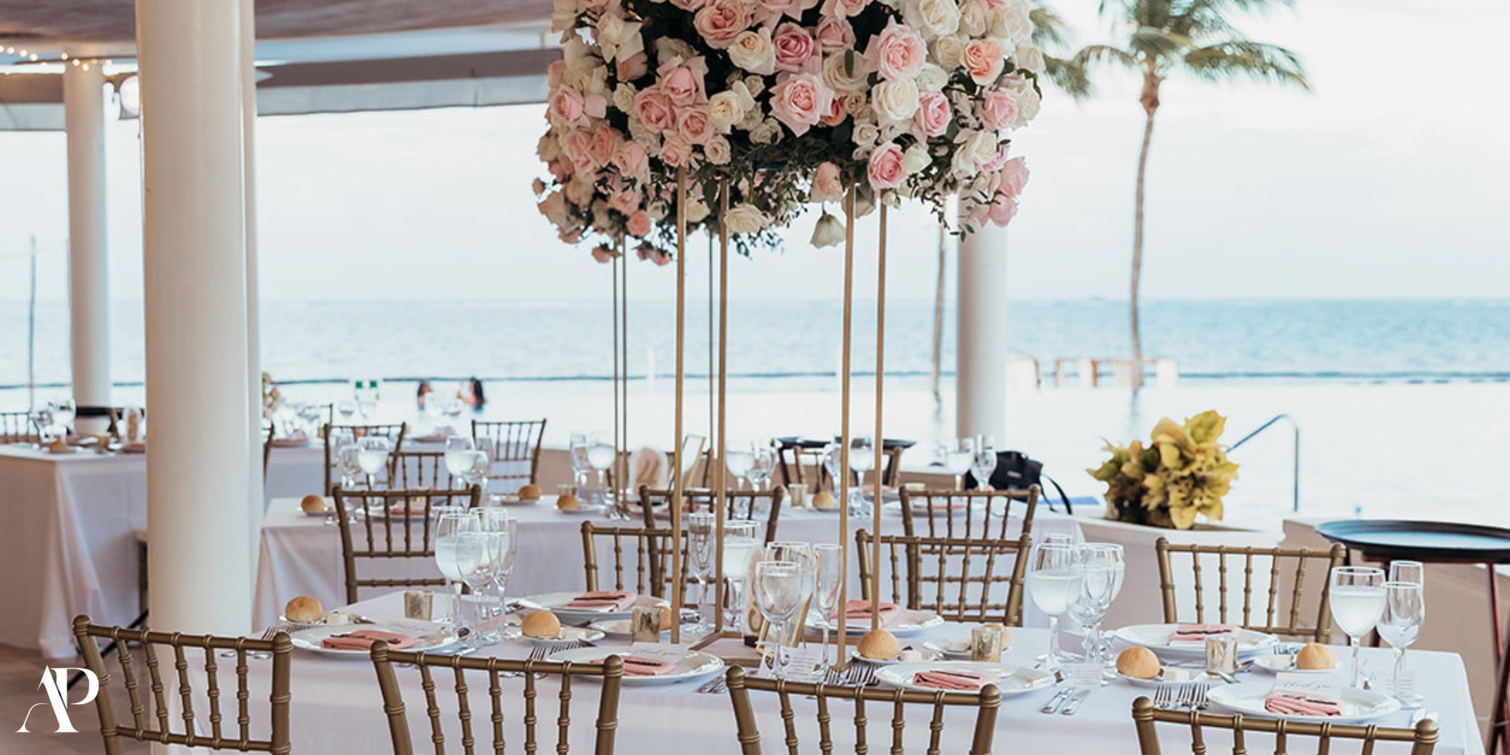 Dreams Riviera Cancun: Elegant destination wedding setup with gold chairs, floral centerpiece, ocean view.