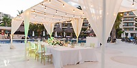 A destination wedding reception table at Dreams Riviera Cancun, glowing under string lights beside the pool.
