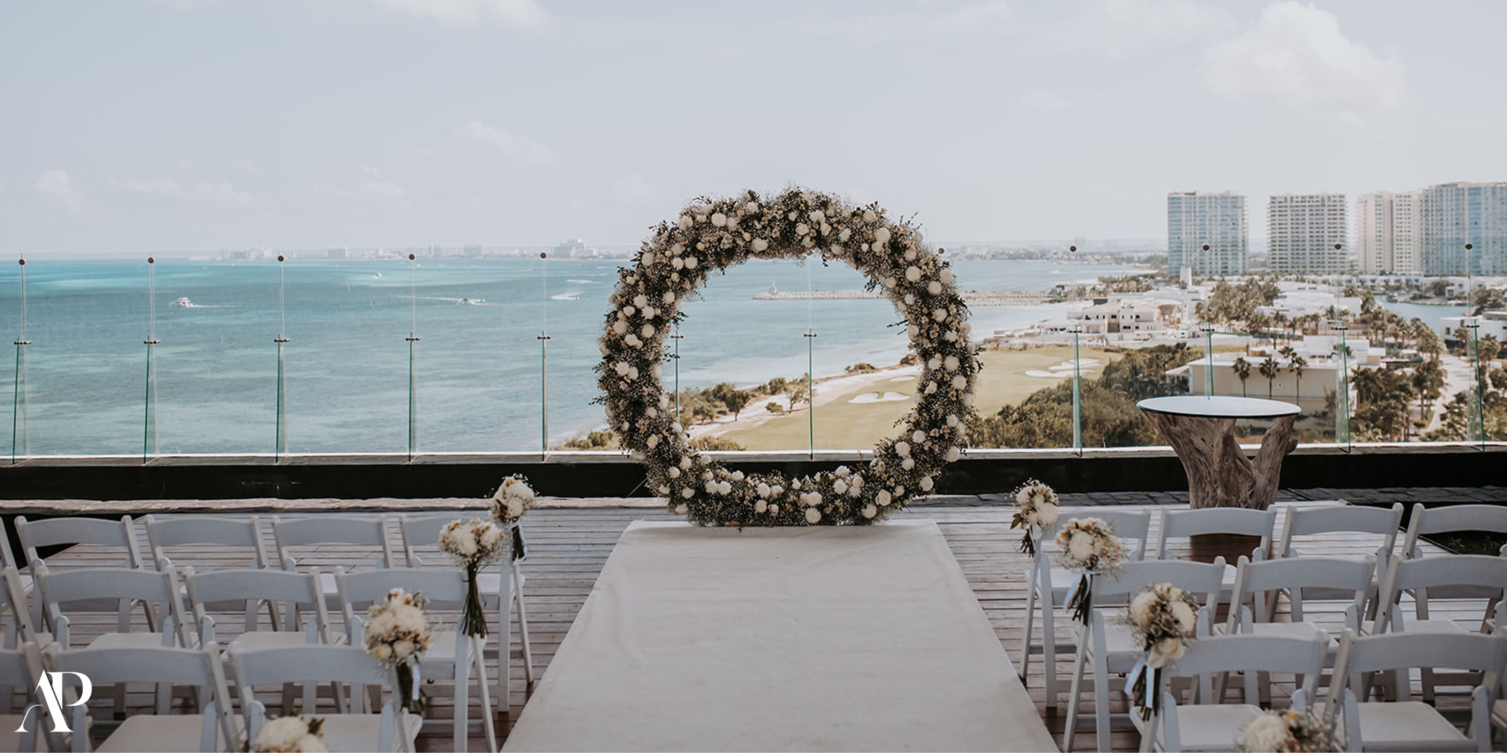 Destination wedding at Dreams Vista Cancun featuring a floral arch, white chairs, and stunning ocean view.