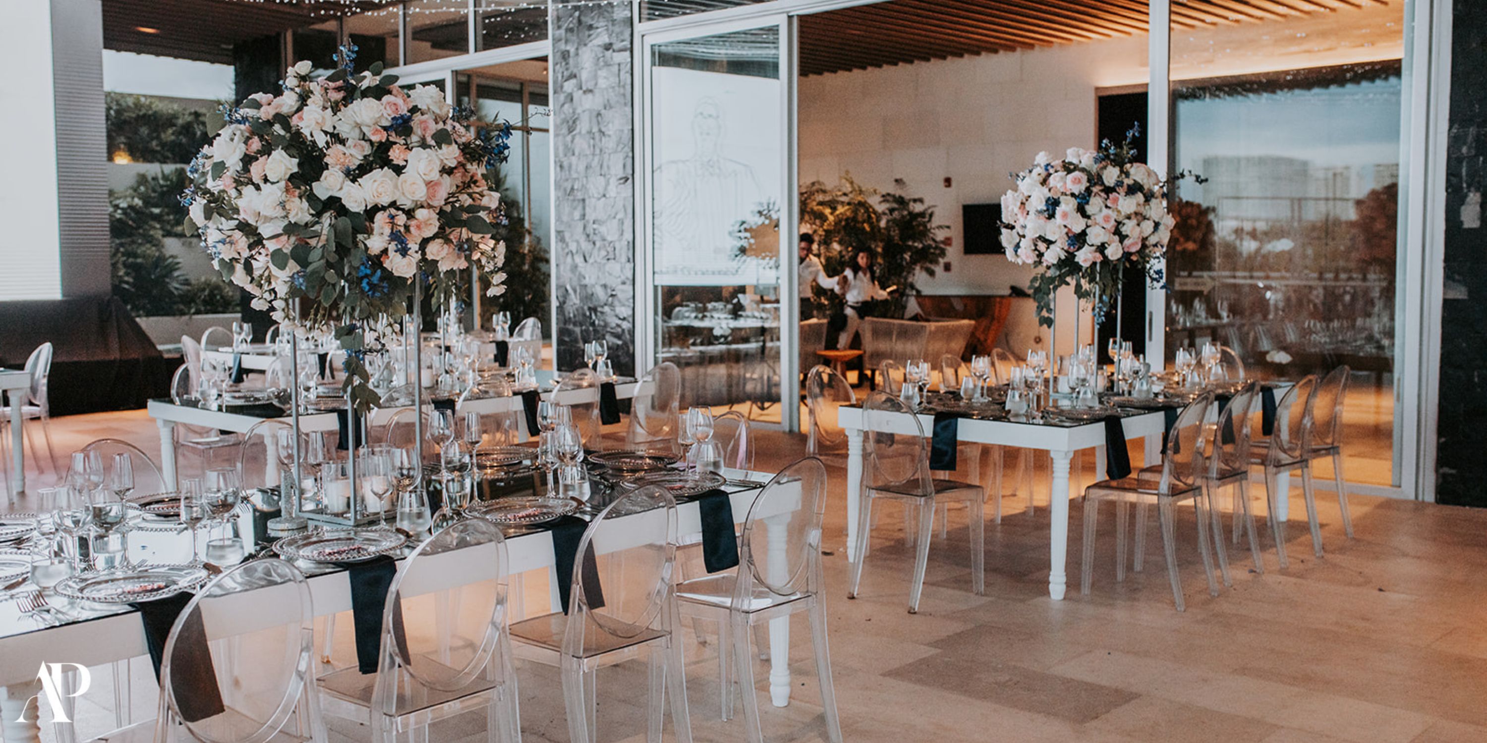 Dreams Vista Cancun destination wedding banquet with floral centerpieces and clear chairs indoors.