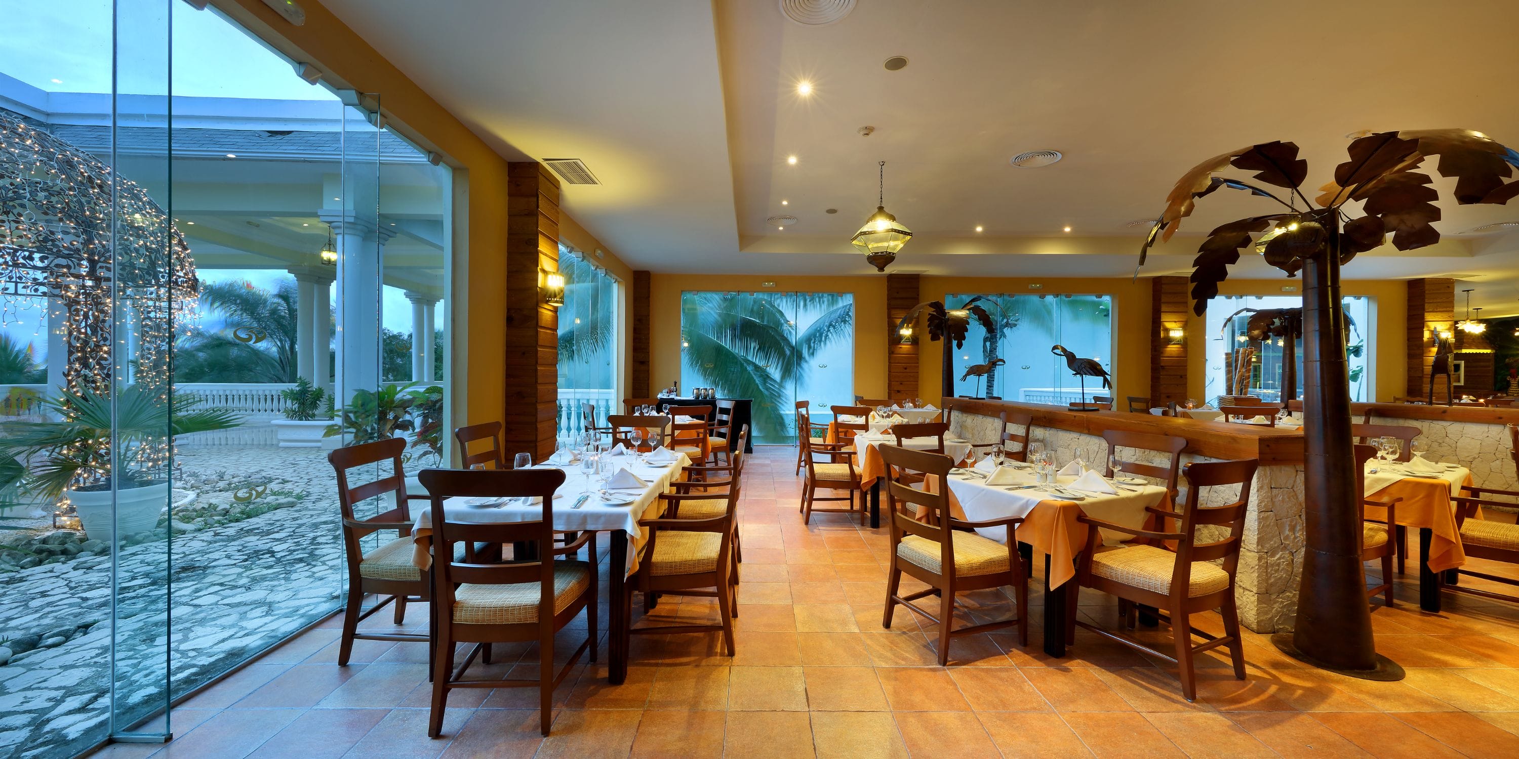 Grand Palladium Jamaica: Elegant wedding dining, wooden tables, chairs, and palm tree views outside.