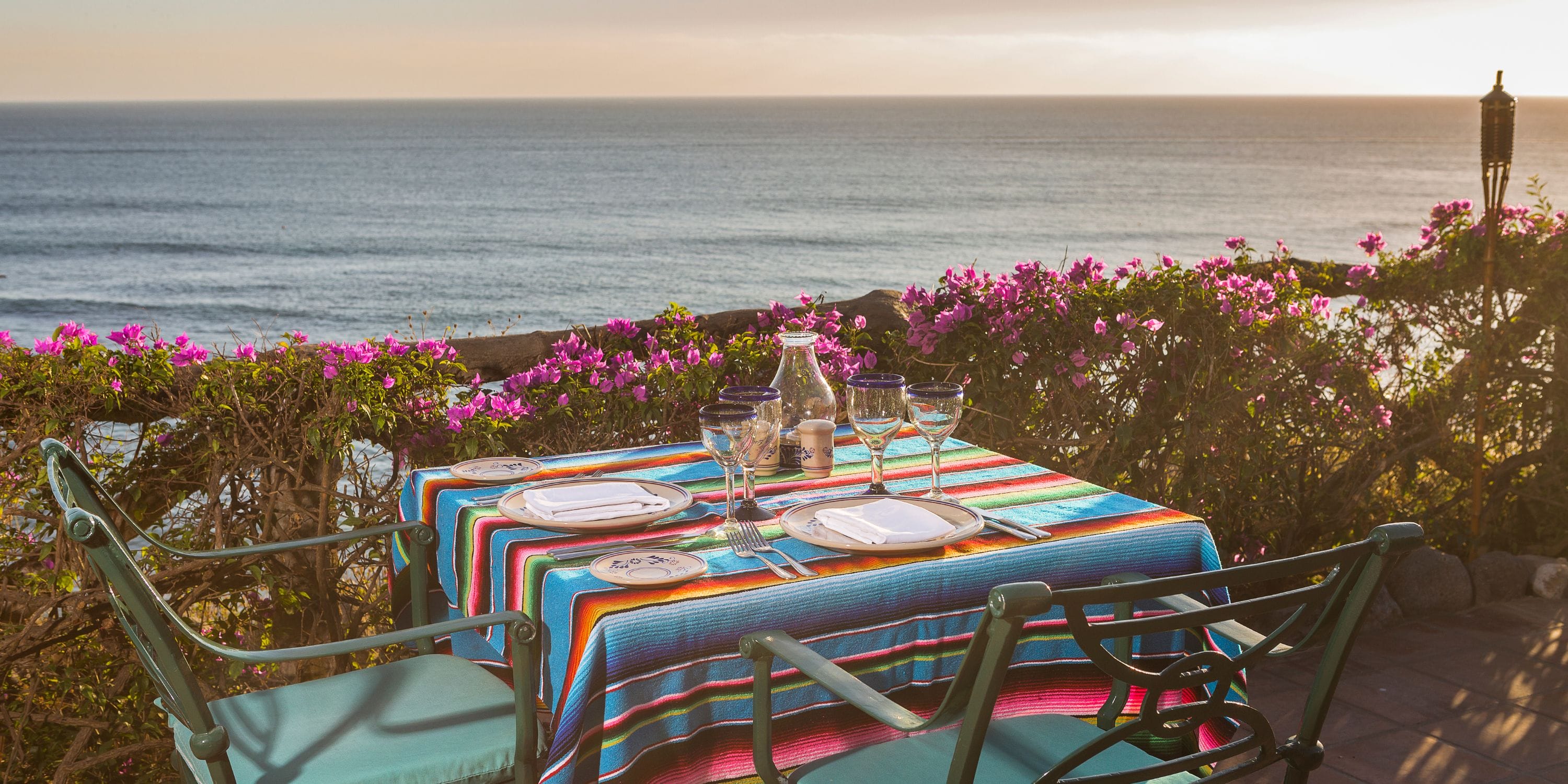 Table for two at a destination wedding, Grand Palladium Vallarta, vibrant cloth, sunset ocean view.