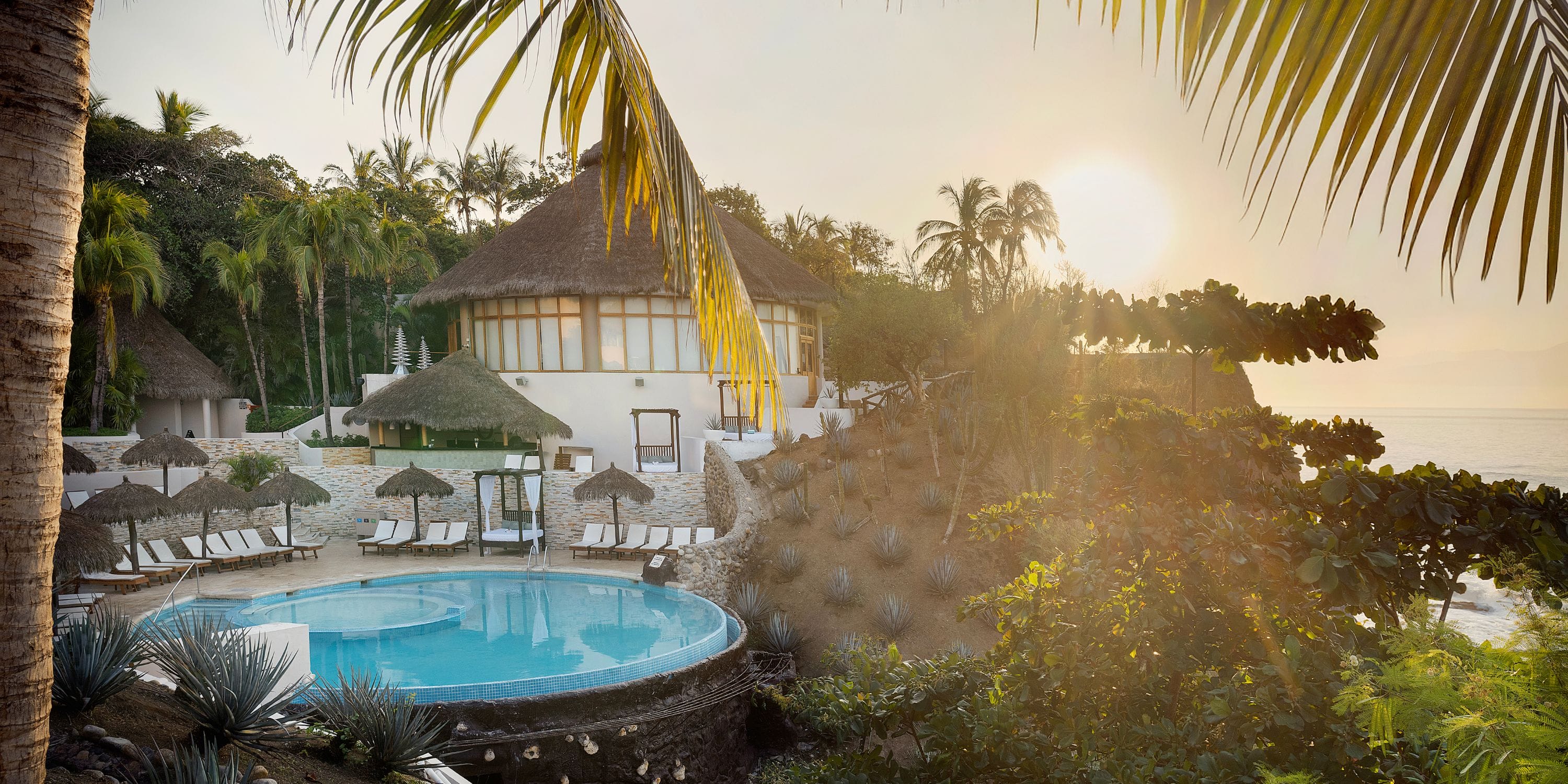 Grand Palladium Vallarta: sunset ocean view, thatched roofs, palms—dreamy destination wedding spot.