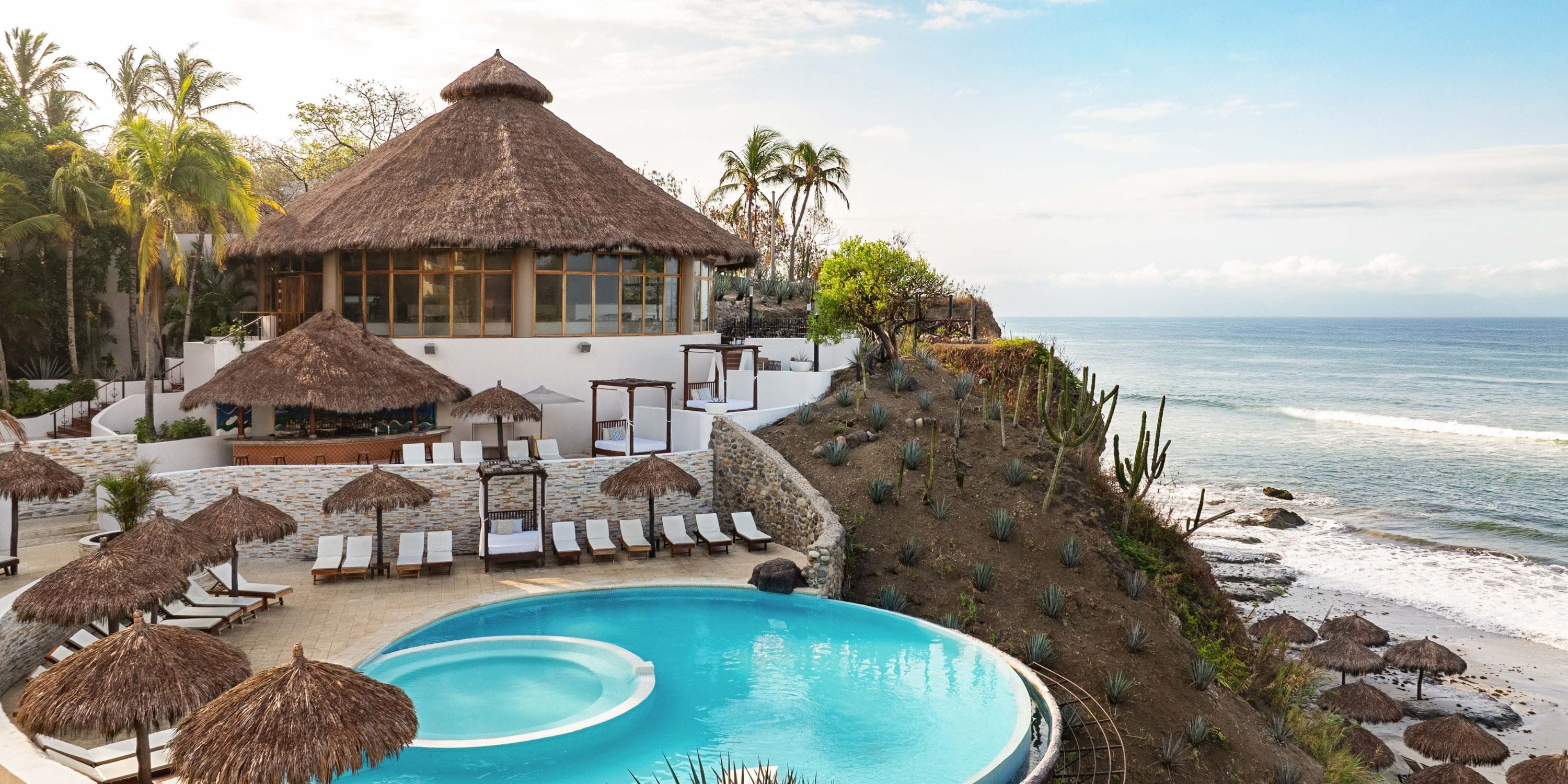Grand Palladium Vallarta: circular pool for a dreamy destination wedding by ocean, thatched roofs.