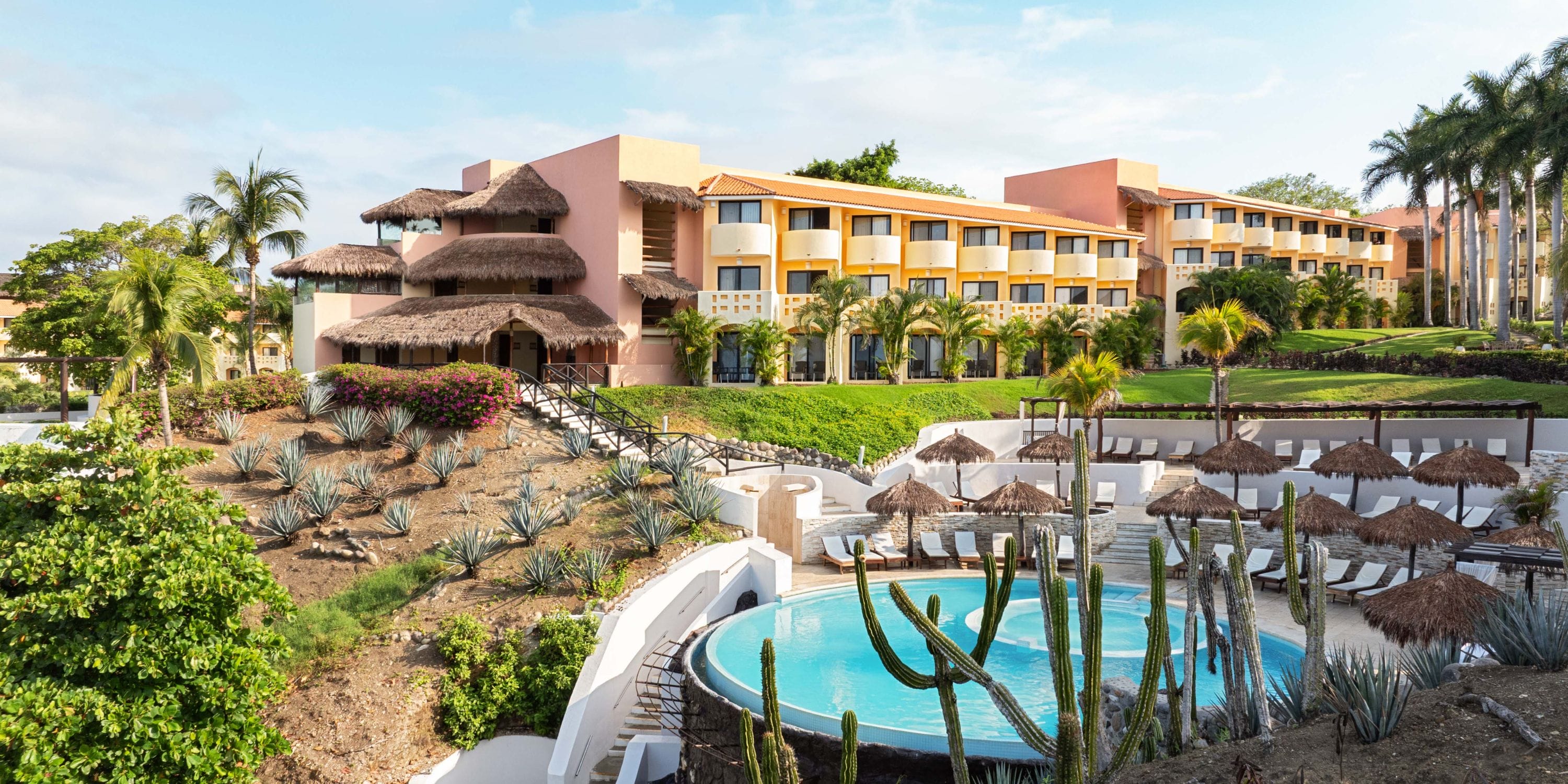 Grand Palladium Vallarta: palm trees, pool, cacti, yellow-orange buildings—ideal for a wedding.
