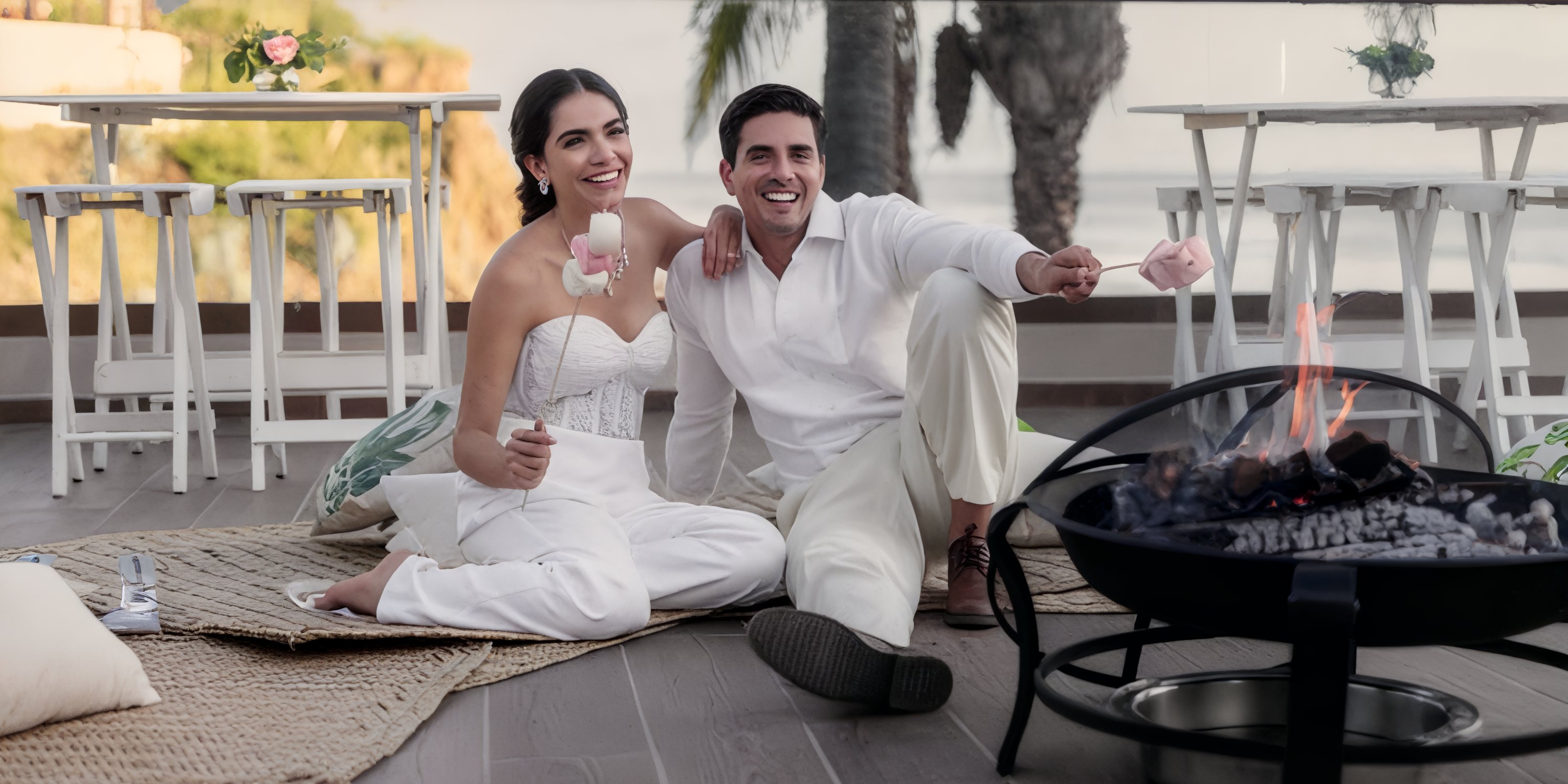 Newlyweds in white roast marshmallows by a fire pit at their Grand Palladium Vallarta destination wedding.