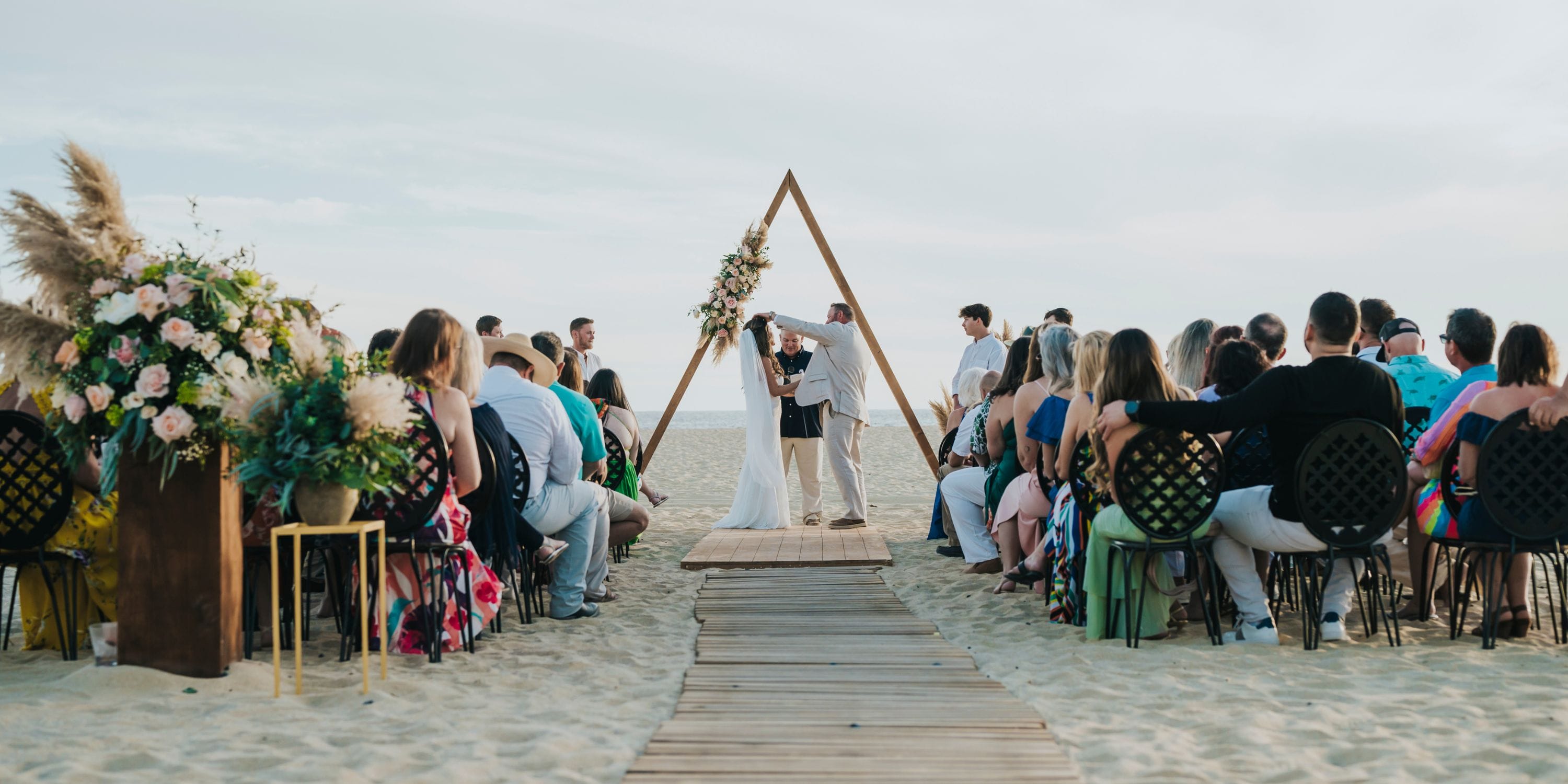 At their destination wedding at Hard Rock Los Cabos, a couple kisses on the beach as guests look on.