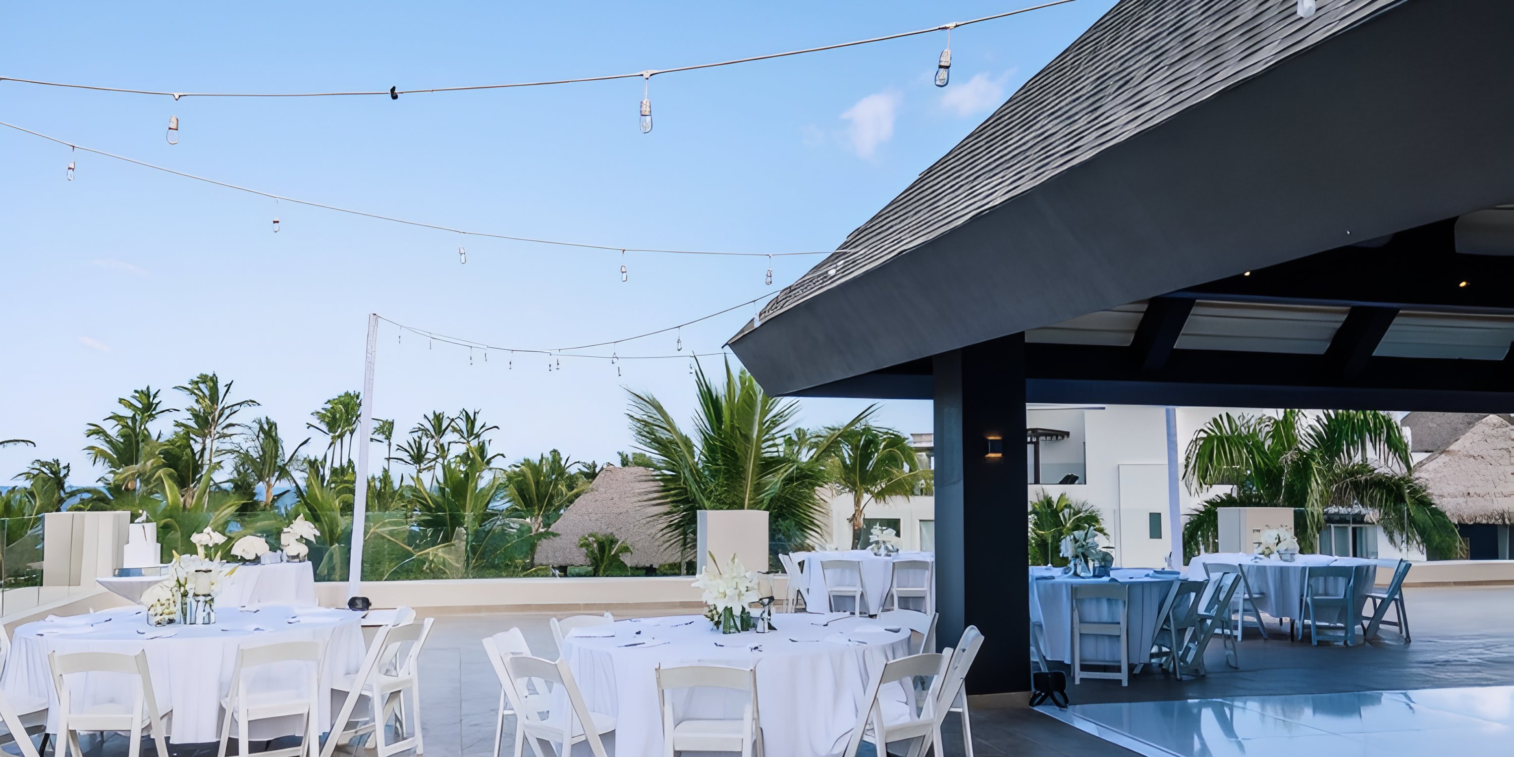 Rooftop at Hard Rock Punta Cana set for a destination wedding&mdash;round tables, white chairs, string lights.