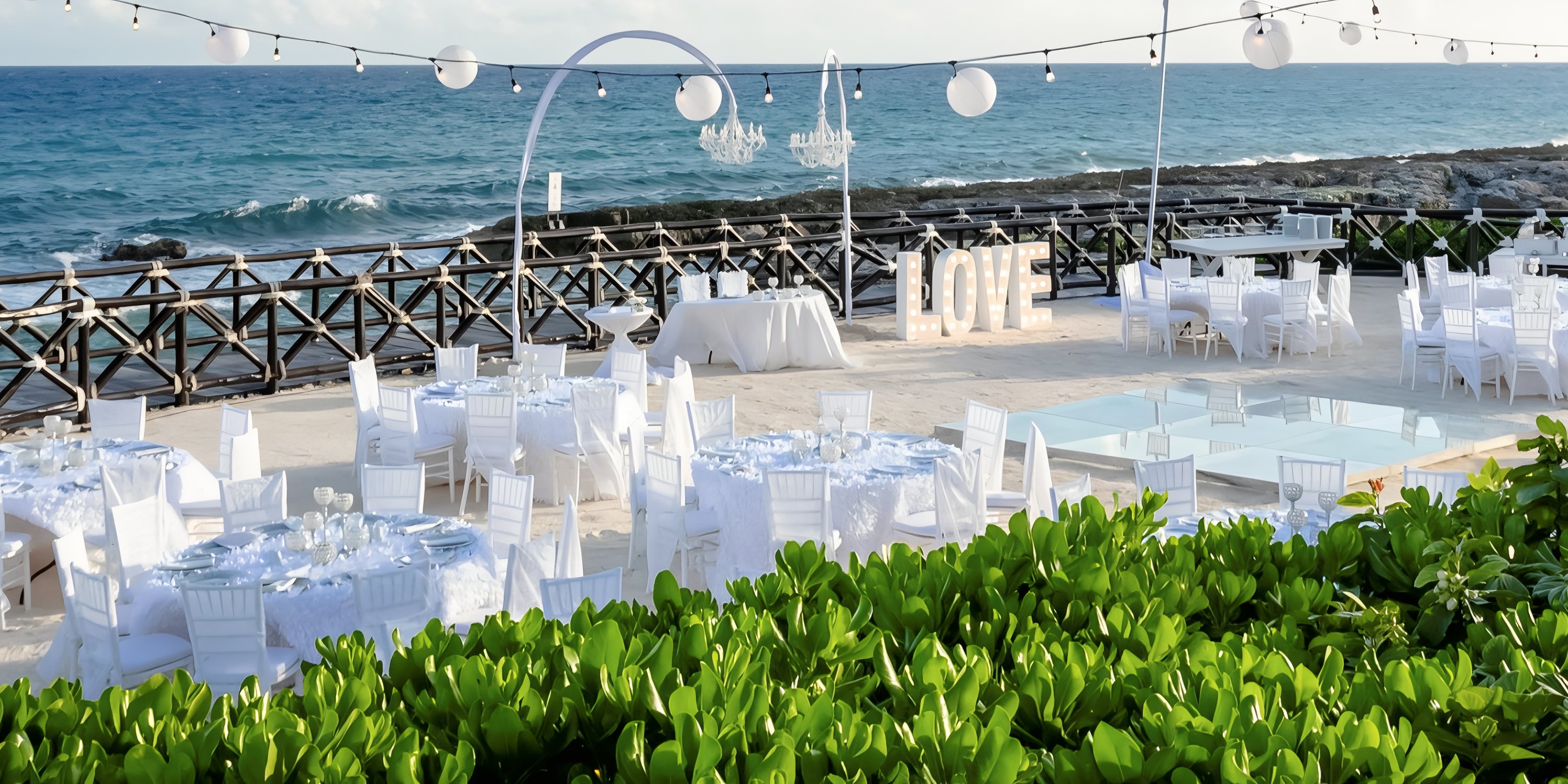 Elegant destination wedding reception by the ocean with white decor at Hard Rock Riviera Maya.