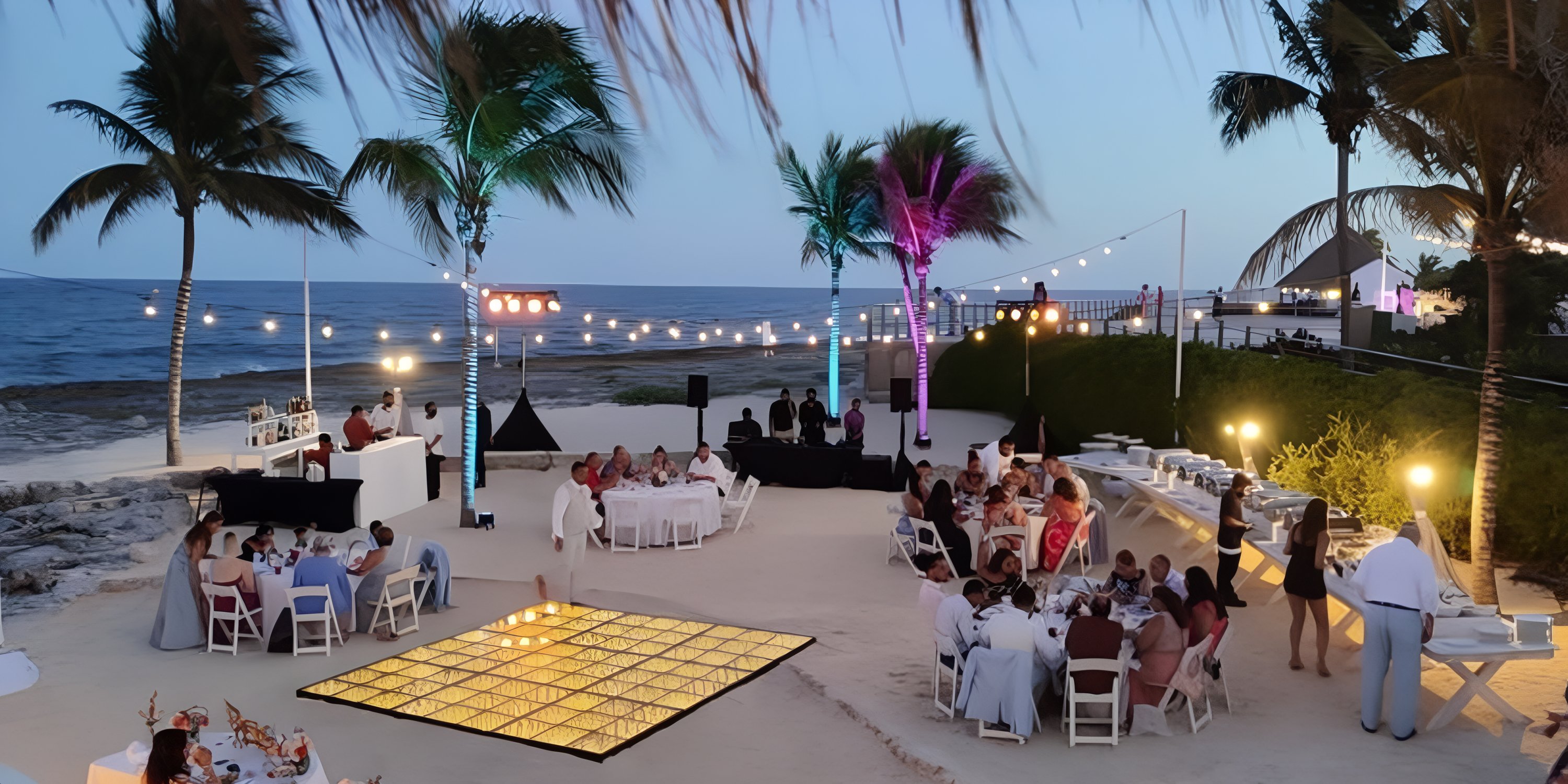 Destination wedding reception at Hard Rock Riviera Maya with dining tables and string lights by the beach.