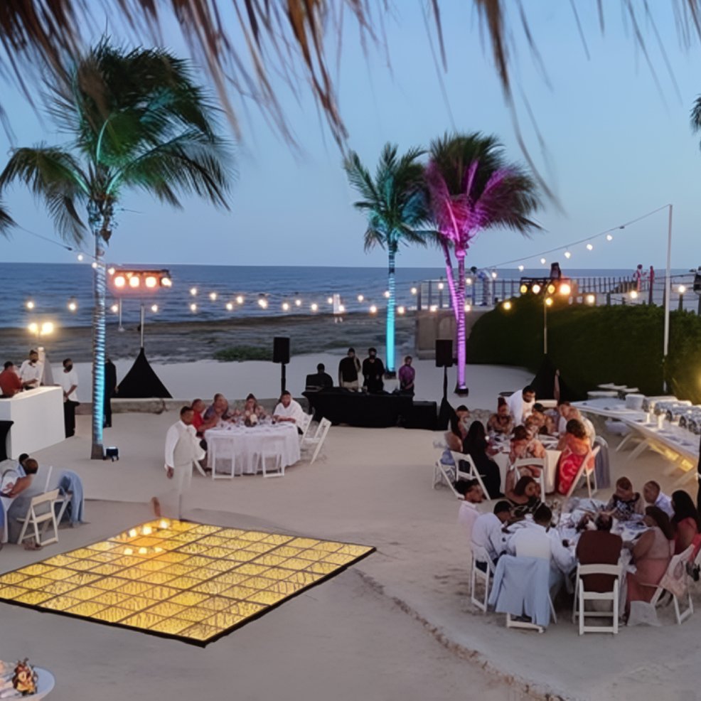 Destination wedding setup at Hard Rock Riviera Maya, featuring tables, string lights, and palm trees.