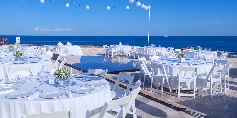 Experience a stunning oceanfront destination wedding at Hard Rock Riviera Maya, complete with elegantly arranged tables, chairs, and enchanting lights.