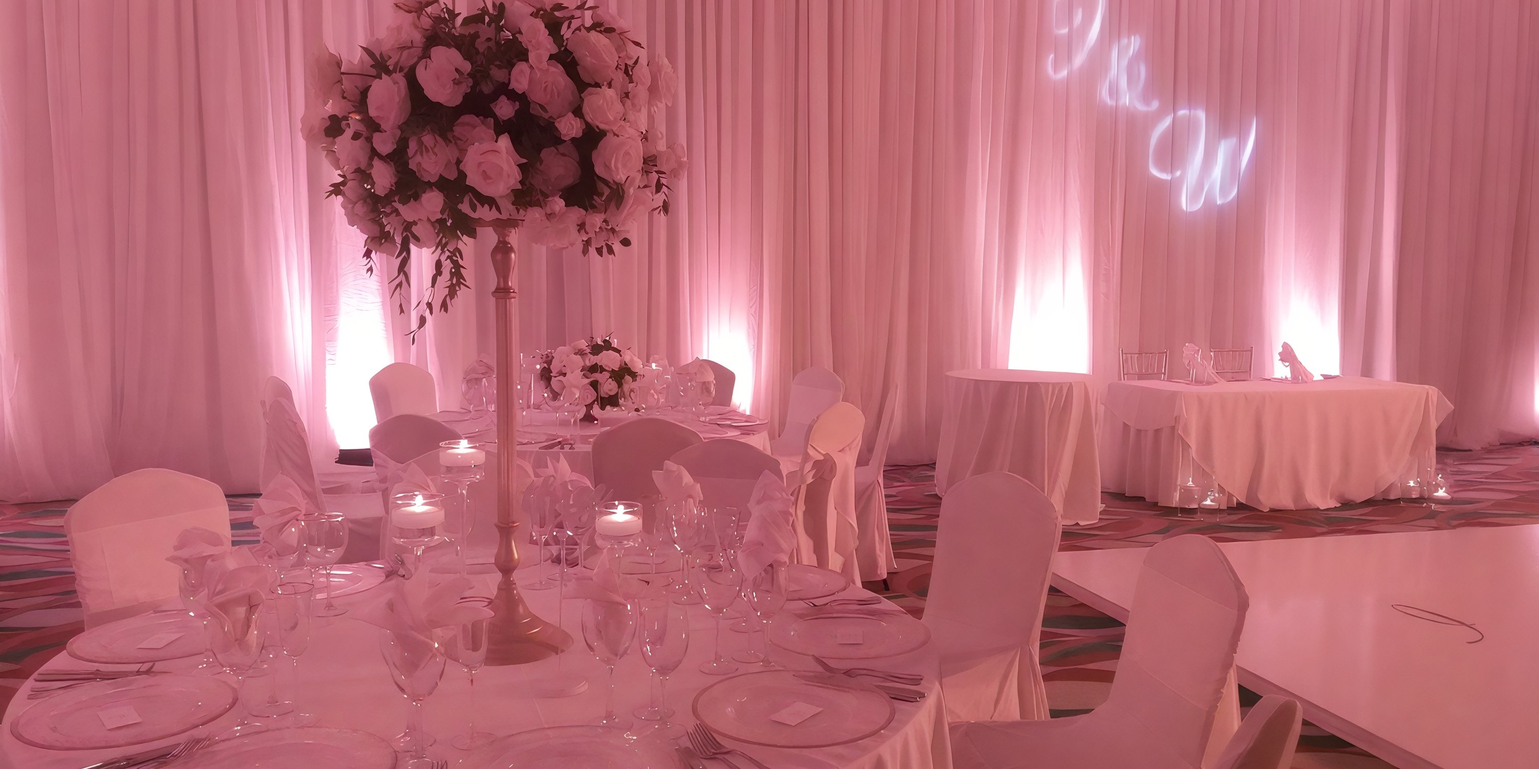 Stunning destination wedding reception at Hyatt Ziva Los Cabos with pink lighting, florals, and round tables.