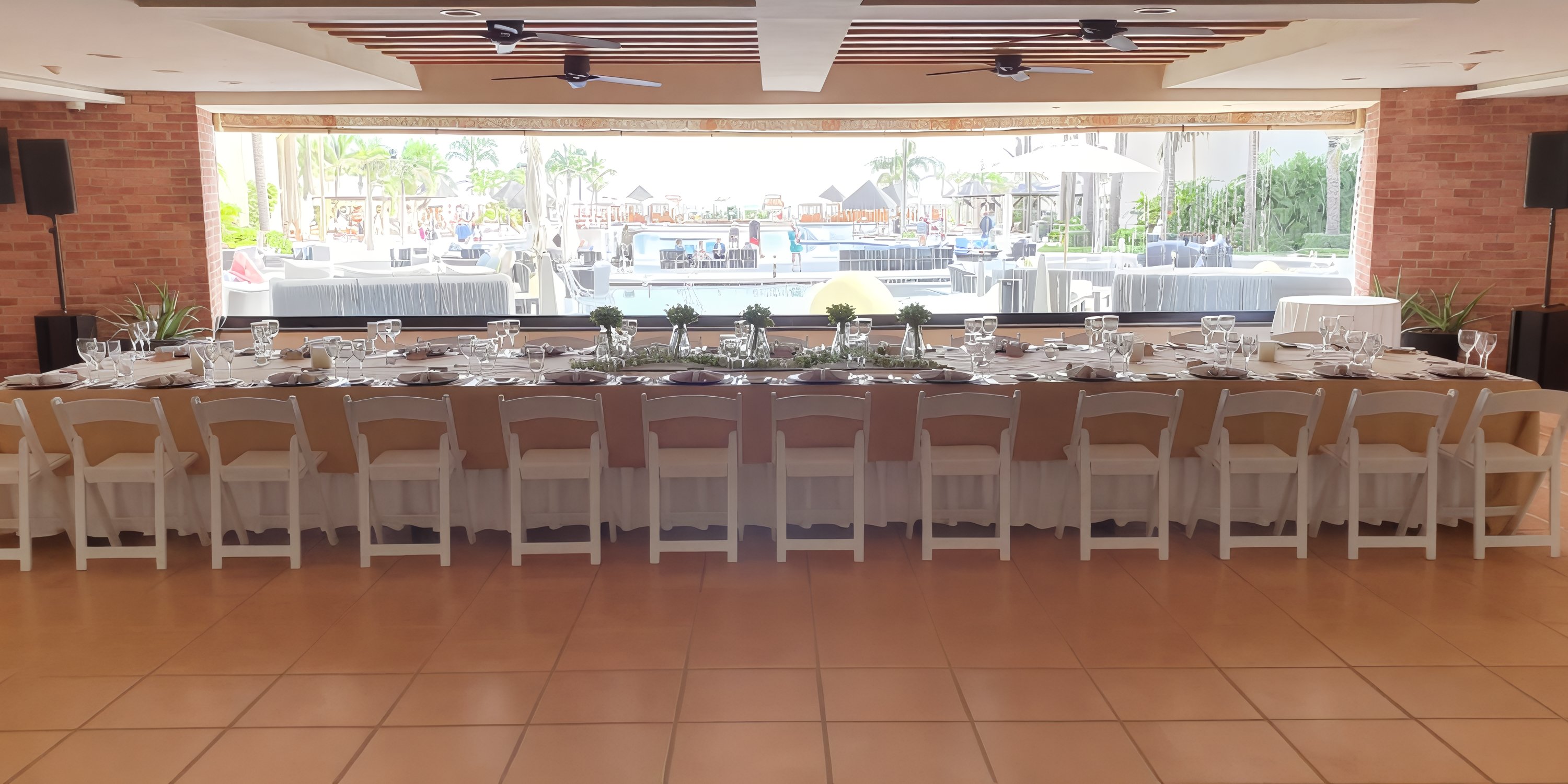 Elegant wedding banquet table at Hyatt Ziva Los Cabos, overlooking the pool and palm trees outside.